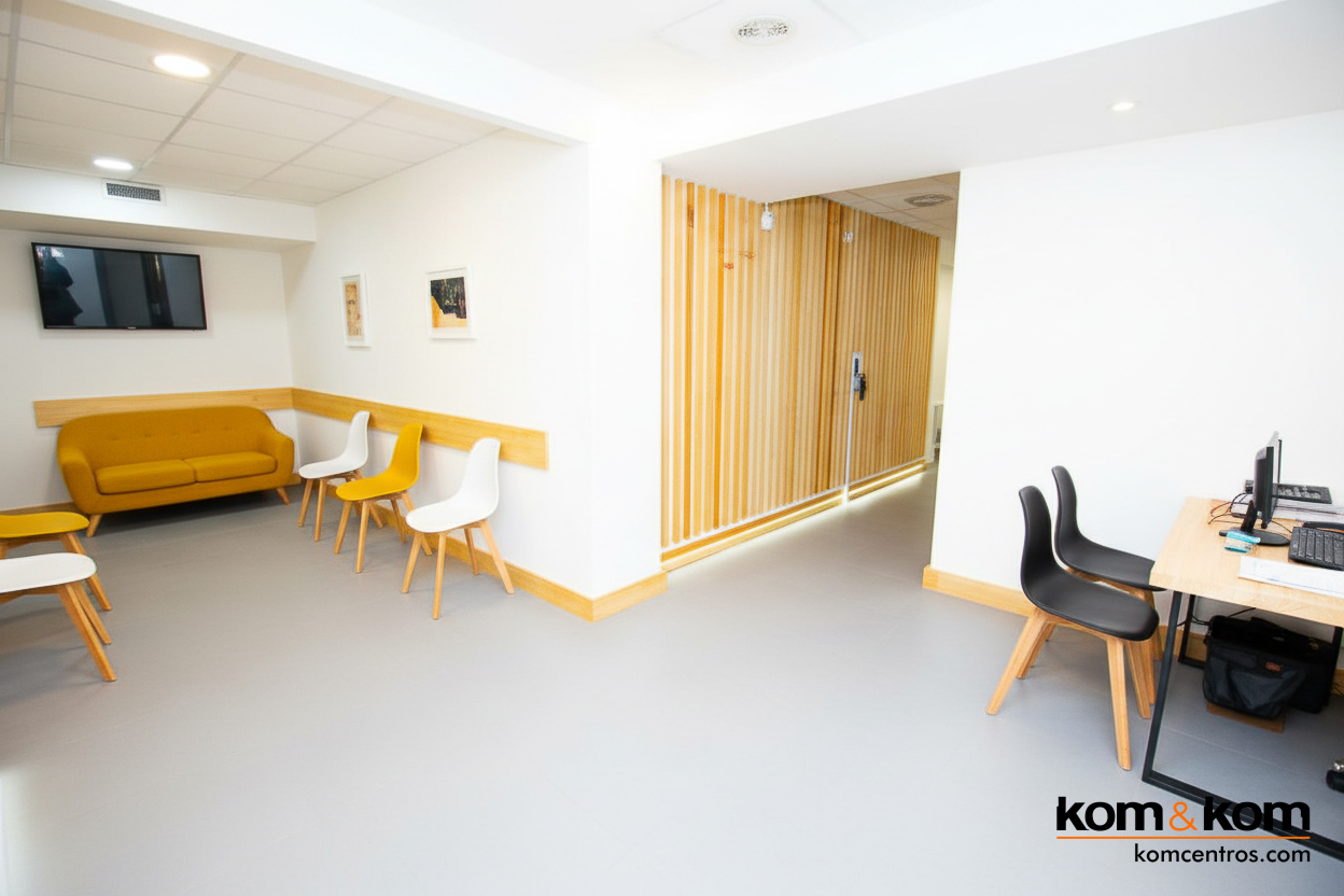 Sala de espera en clínica dental con sofá en color mostaza, sillas de madera y diseño acogedor. Predominan los colores blanco y madera clara.
